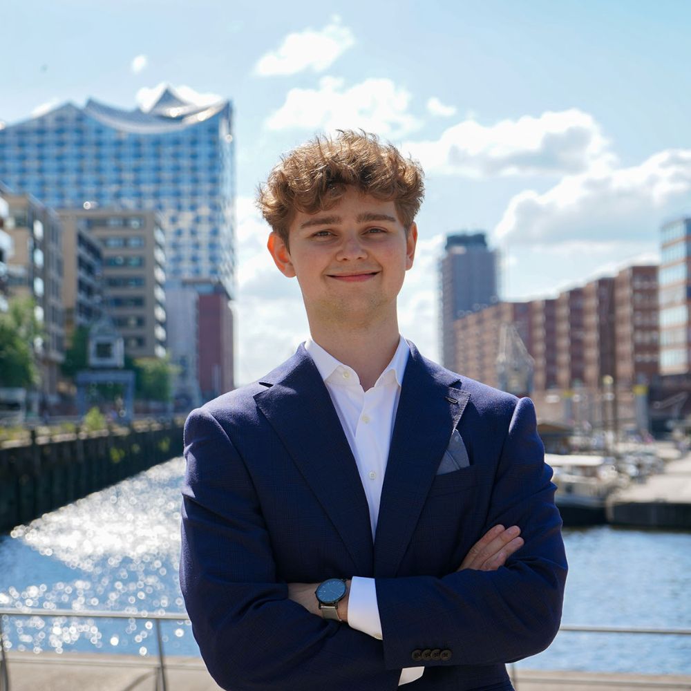 Ein Mann lächelt in der Hamburger Innenstadt in die Kamera